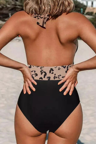 Leopard print halter neck one-piece swimwear with a stylish cutout design, showcasing the model's toned back and shoulders.