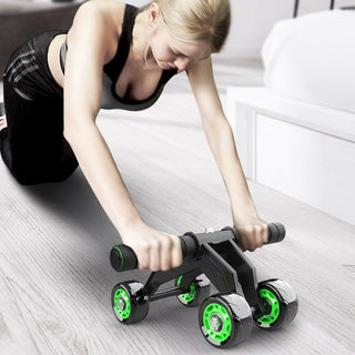 Fitness roller with bold green wheels on white floor, woman using exercise equipment for strength training and core workout