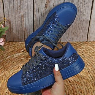Glittering blue sequin-embellished sneakers with thick soles on a wooden surface. These trendy, casual shoes feature a lace-up design for a secure fit, perfect for everyday fashion and skateboarding.