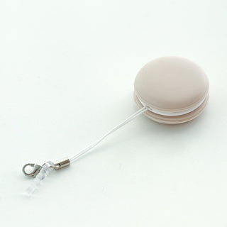 Compact macaron-shaped screen cleaner with retractable wire for mobile devices.