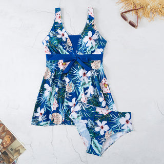 Vibrant tropical print bikini with floral and pineapple motifs, sleek design featuring a split front and bow waist, perfect for stylish beach or poolside attire.