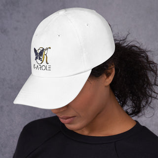 Stylish white dad hat with K-AROLE logo, worn by a person with dark, curly hair against a gray background.