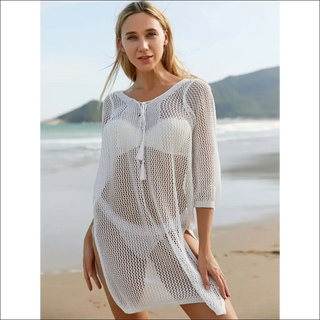 Stylish white mesh beachwear with three-quarter sleeves and tie neck detail on model by the ocean.