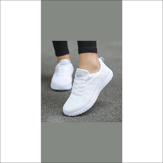 Comfortable white mesh women's sneakers for casual walking and gym activities, displayed on a grey background.