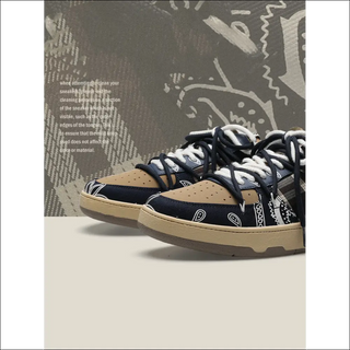 Stylish fitness sneakers with navy blue and tan colors, featuring a distinctive patterned design on the upper. The sneakers are placed against a textured, graffiti-style background, adding a dynamic visual element to the image.