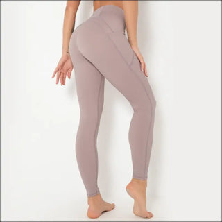 Form-fitting beige yoga pants with an athletic, high-waisted design showcasing the model's toned physique.