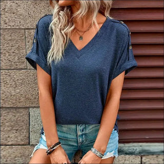 Navy blue V-neck casual top with short sleeves, worn by a woman with long blonde hair against a wooden background.