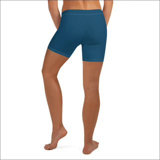 Teal blue athletic shorts worn by a female model, showcasing the form-fitting design and revealing the wearer's toned legs.