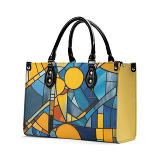 Stylish leather tote bag featuring a colorful stained glass-inspired print in shades of yellow, blue, and black. Sleek black handles and hardware complement the modern design. A fashionable and functional accessory to elevate any outfit.